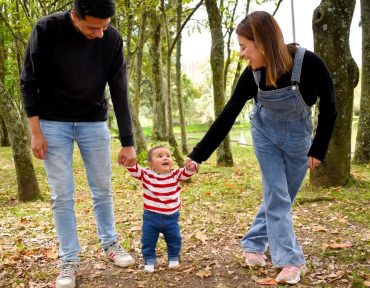 A joyful family enjoys a walk under lush green trees in the park.
